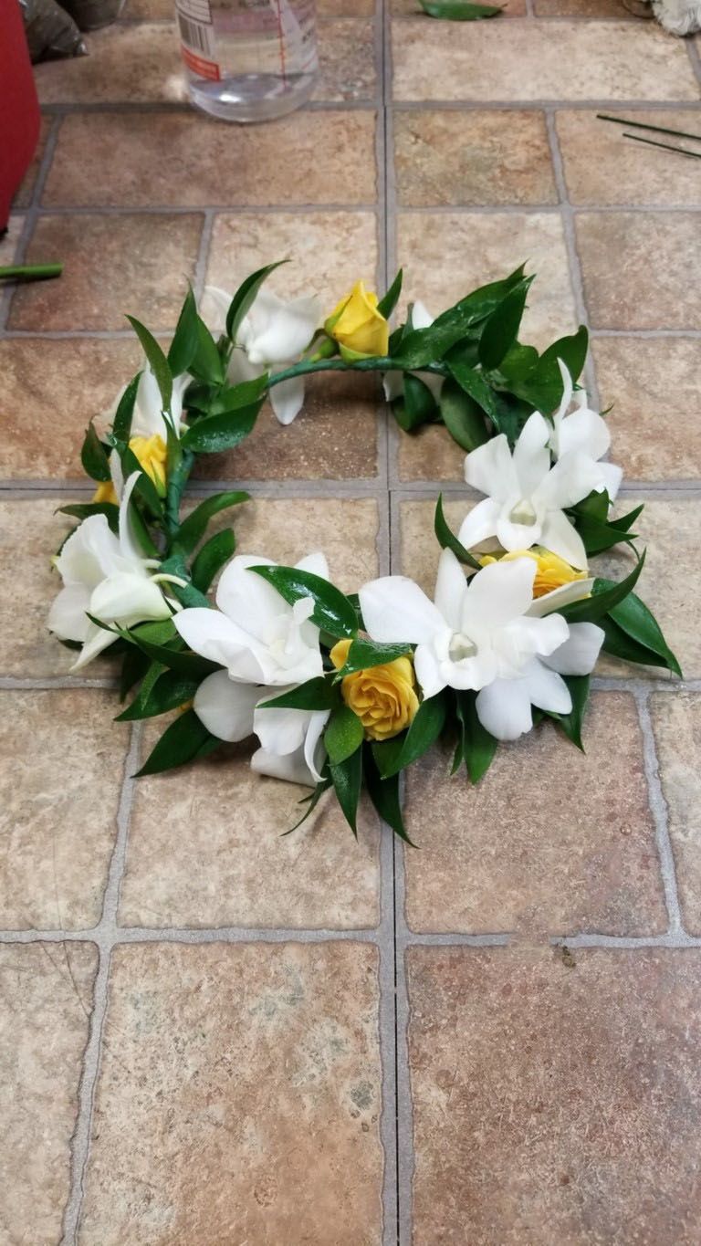 A wreath of white and yellow flowers is sitting on a tiled floor.