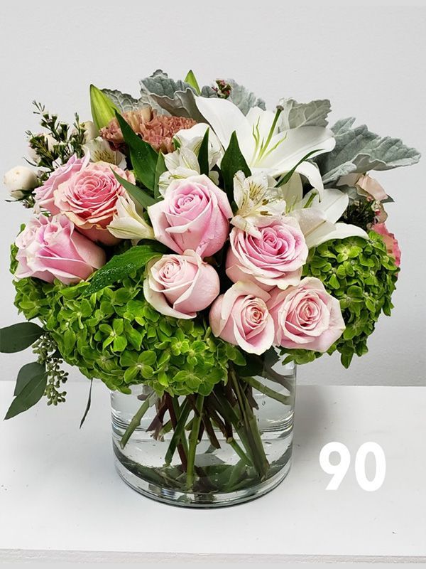 A vase filled with pink roses and white lilies