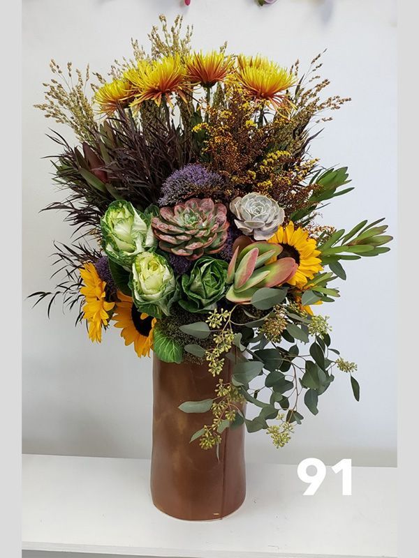 A vase filled with flowers and succulents is sitting on a table.