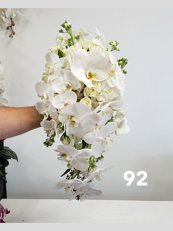 A person is holding a bouquet of white flowers in their hand.