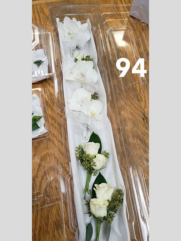 A bunch of white flowers in a plastic container on a wooden table.
