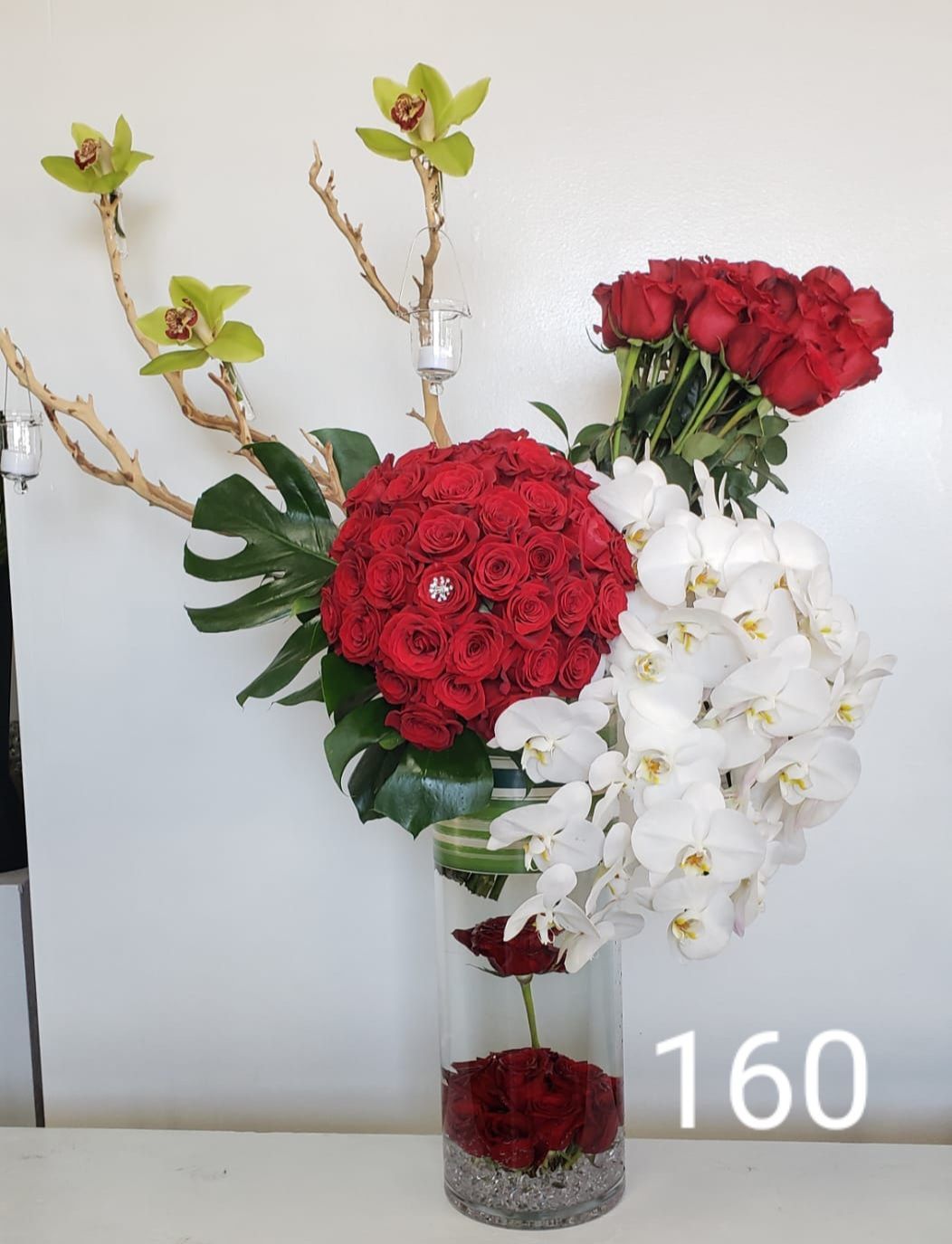 A vase filled with red roses and white orchids