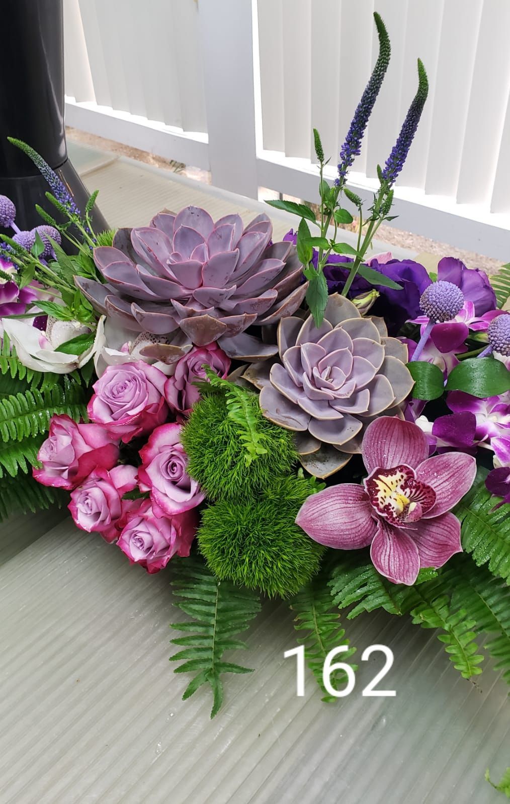 A bouquet of purple flowers and succulents is sitting on a table.