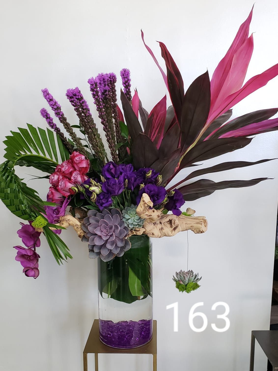A vase filled with purple and pink flowers is on a table.