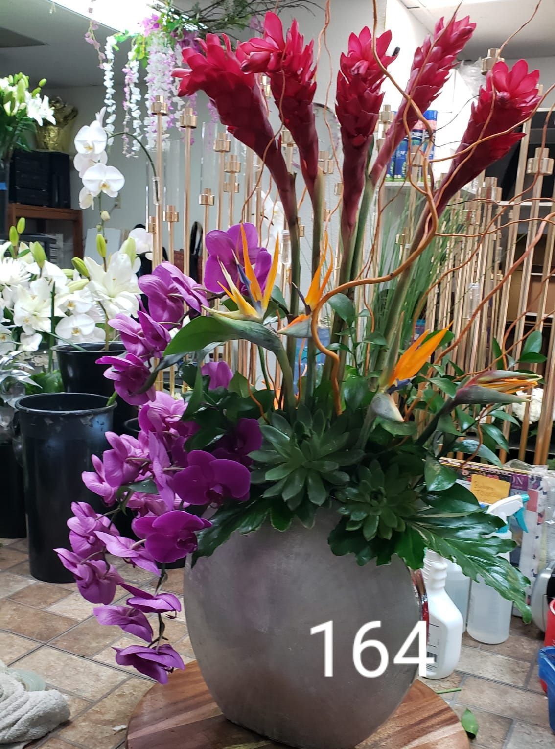 A vase filled with purple and red flowers has the number 164 on it