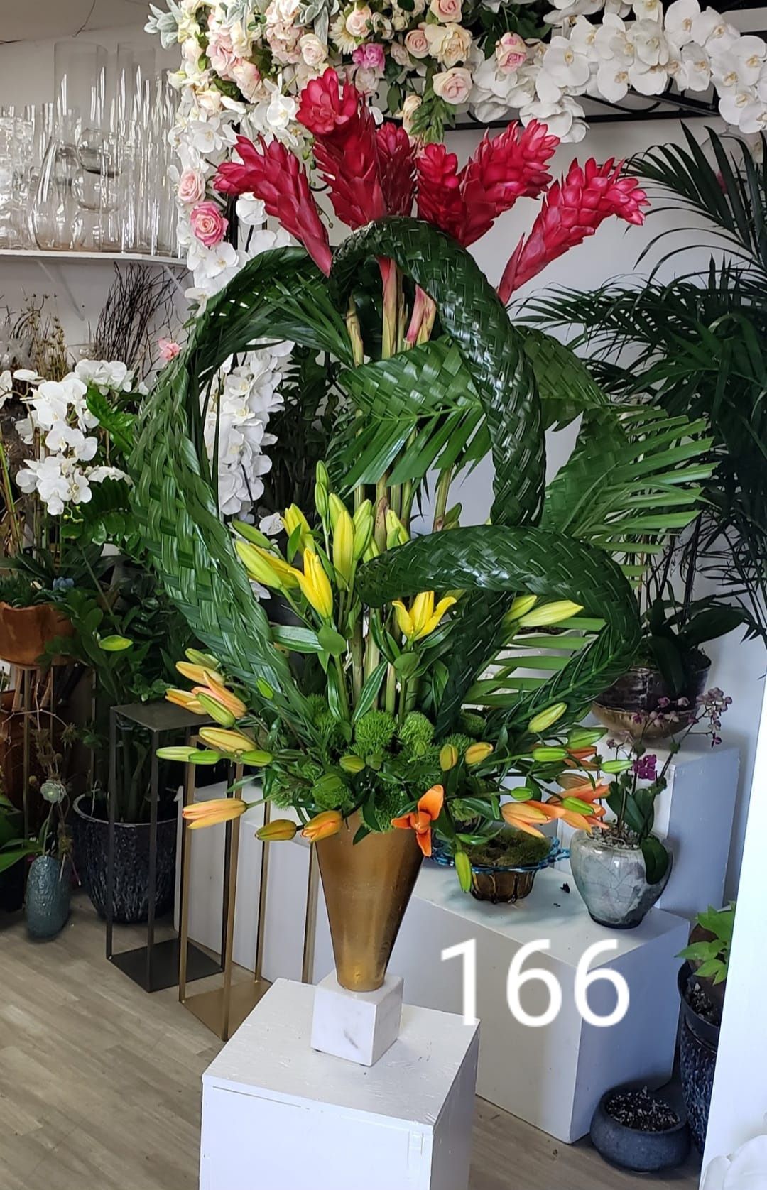 A large vase filled with flowers and leaves is sitting on top of a table.