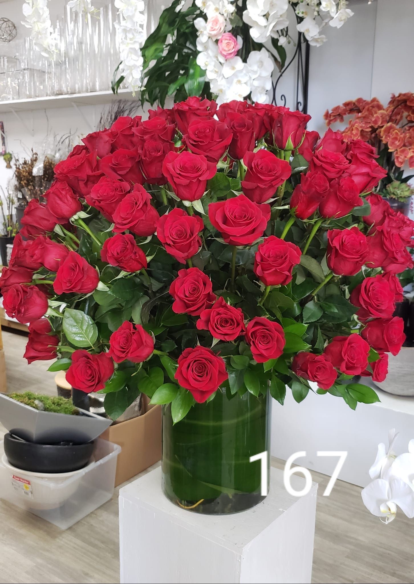 A vase filled with lots of red roses is sitting on a table.