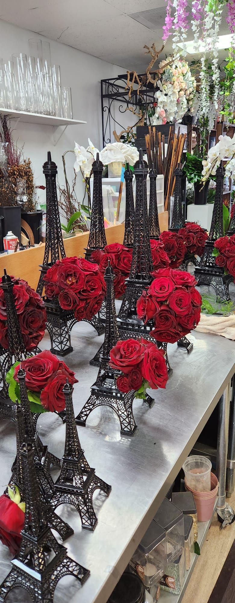 A row of eiffel towers filled with red roses on a table.