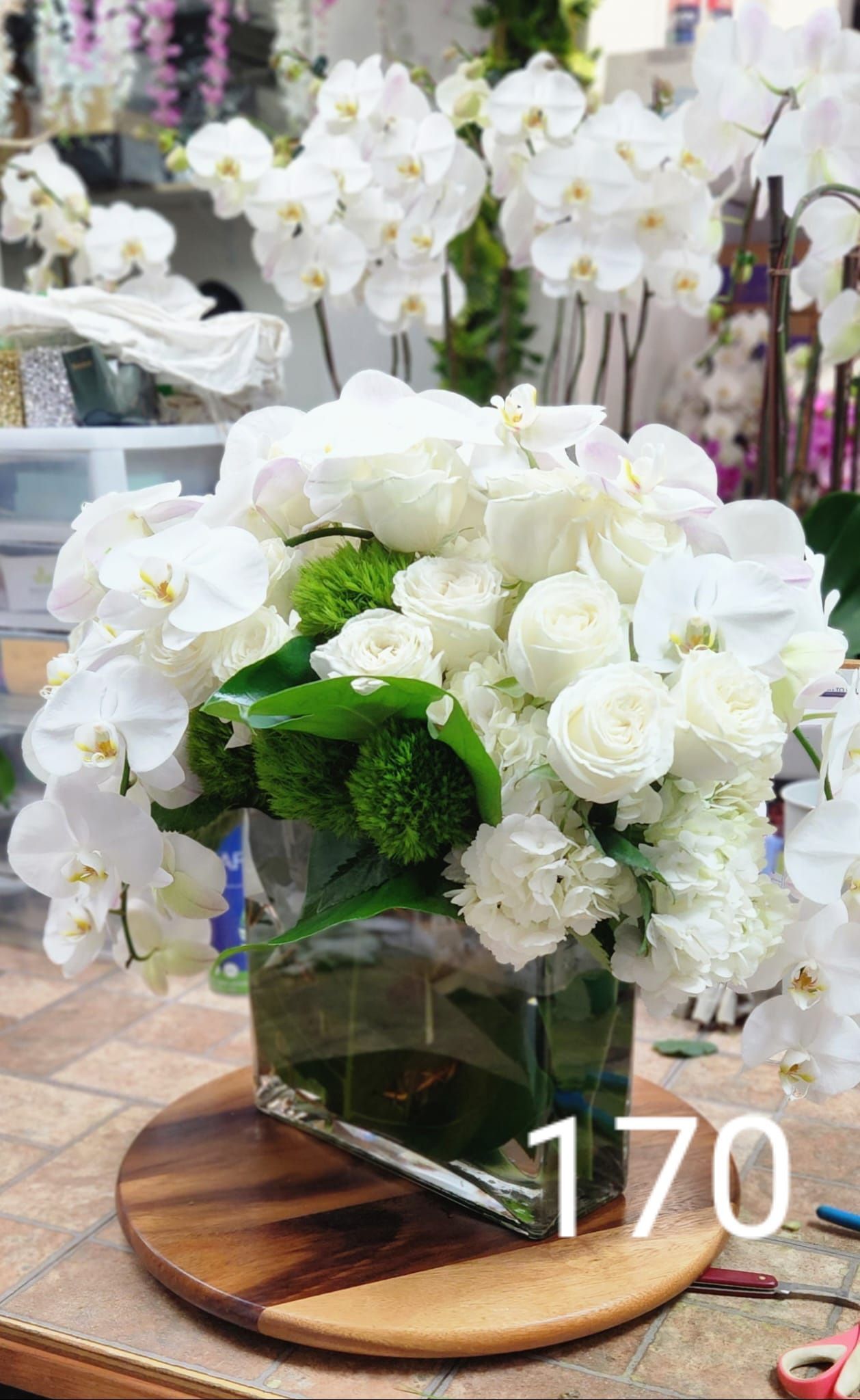A vase filled with white flowers is sitting on a wooden table.