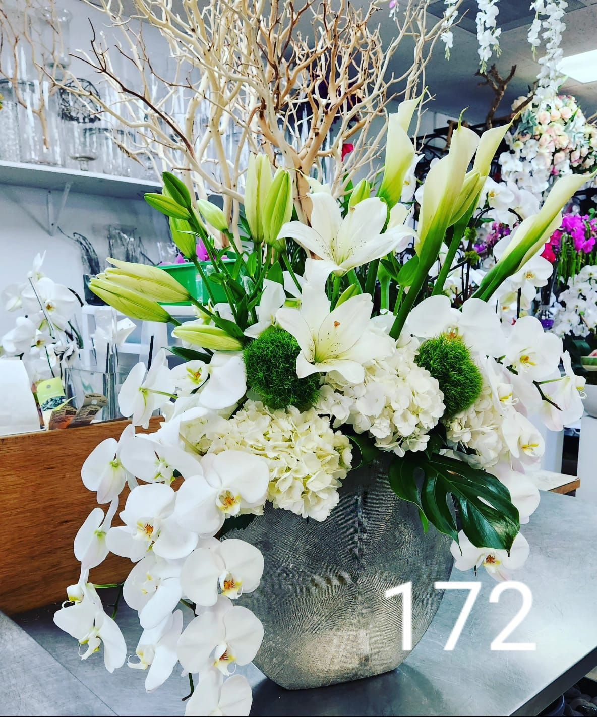 A vase filled with white flowers and the number 172 on the bottom