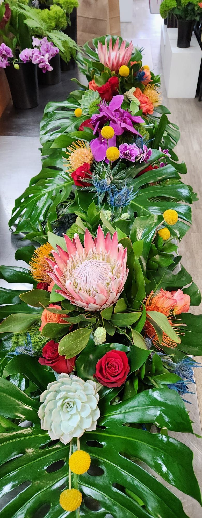A long table topped with lots of flowers and leaves.