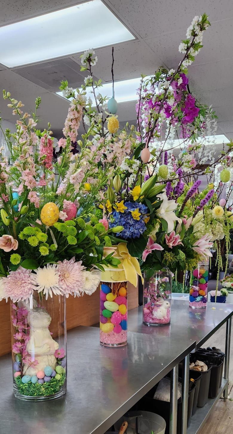 A bunch of vases filled with flowers and candy on a table.