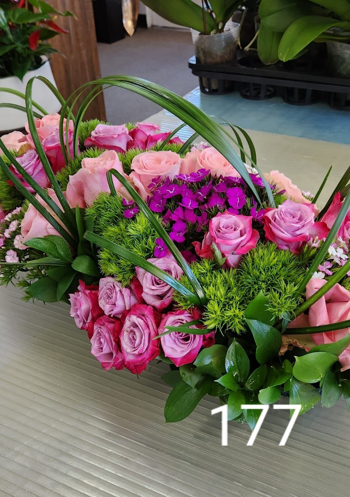 A bouquet of pink roses and purple flowers is sitting on a table.