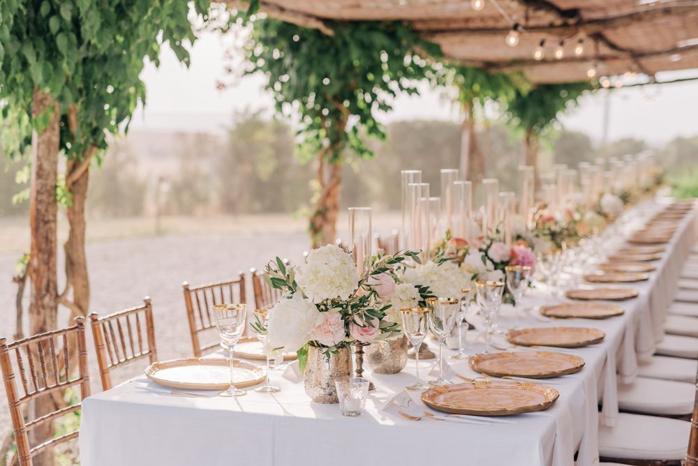 A long table set for a wedding reception under a canopy.