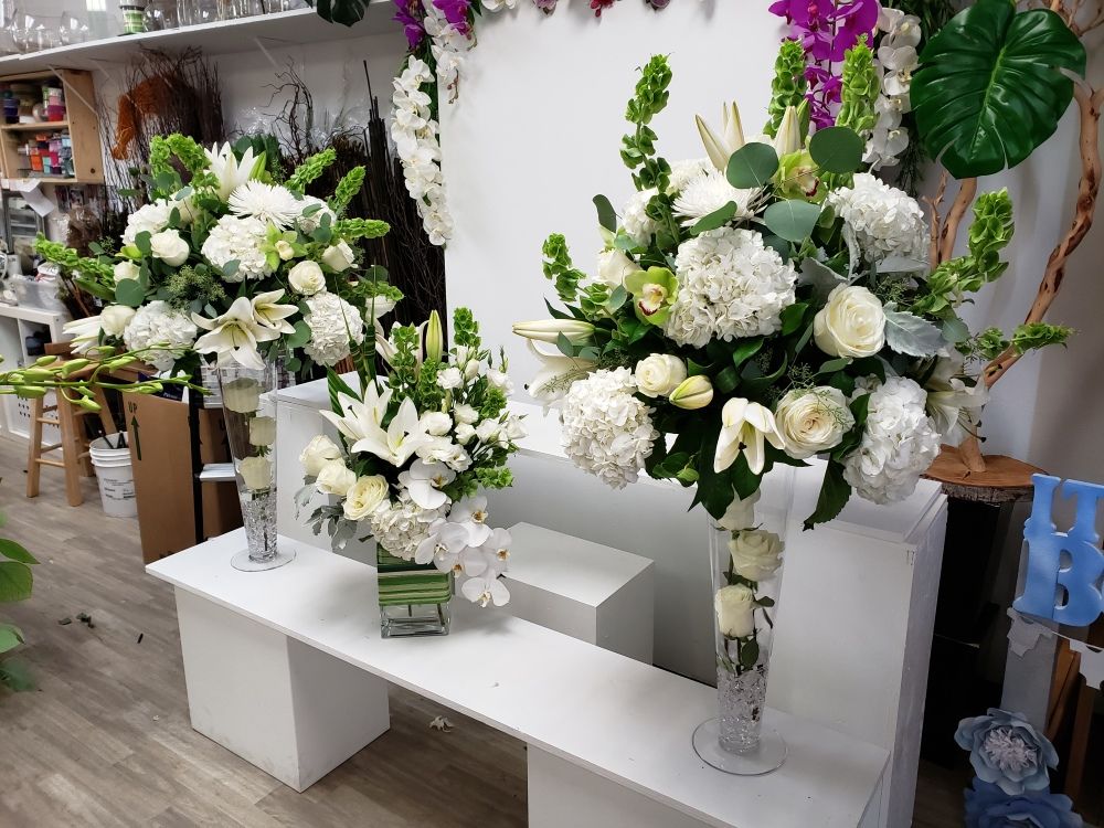 Three vases filled with white flowers are sitting on a table.