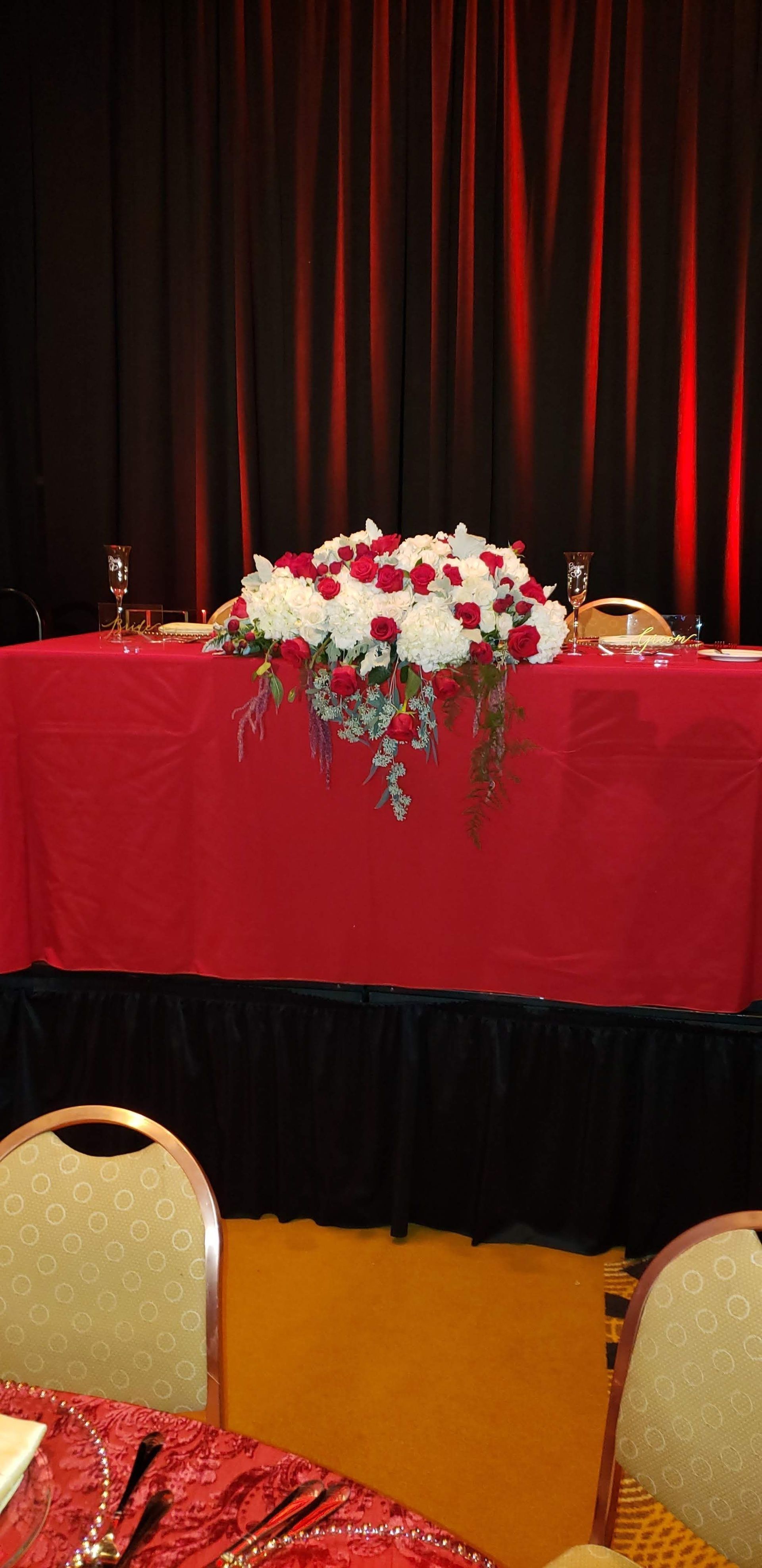 A table with a red tablecloth and flowers on it.