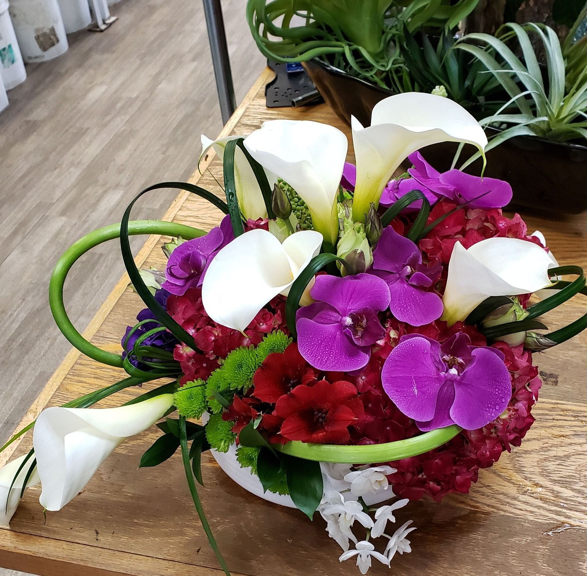 A vase filled with purple and white flowers sits on a wooden table