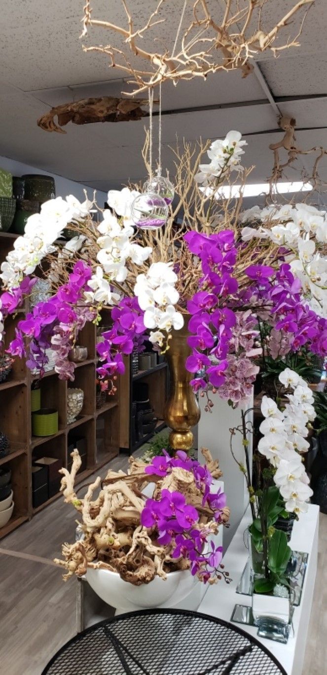 A vase filled with purple and white flowers is sitting on a table in a room.