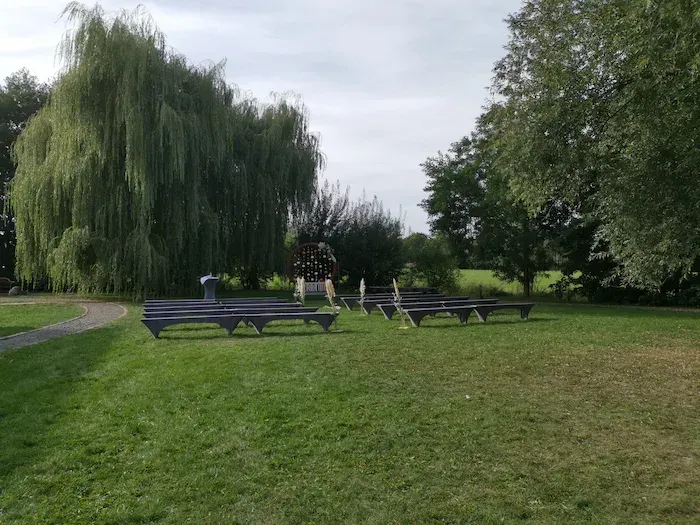 Paulinenhof Kuhlowitz bei Bad Belzig – Outdoor-Trauplatz auf der Wiese mit Bestuhlung, Weidenbaum und natürlicher Hochzeitskulisse in Brandenburg