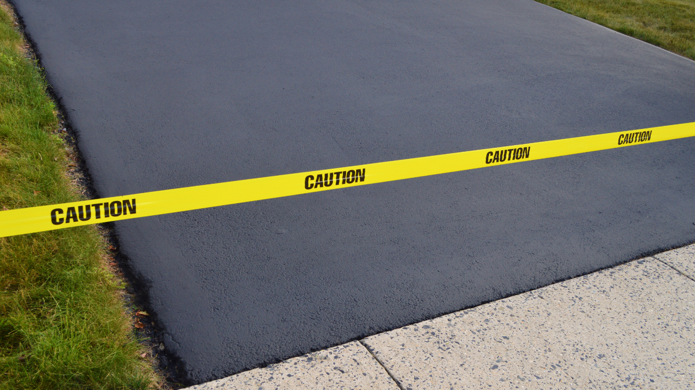 A yellow caution tape is on a blacktop driveway