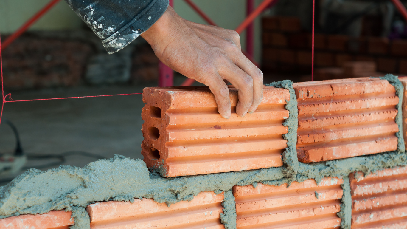 A person is laying bricks on top of each other on a wall.