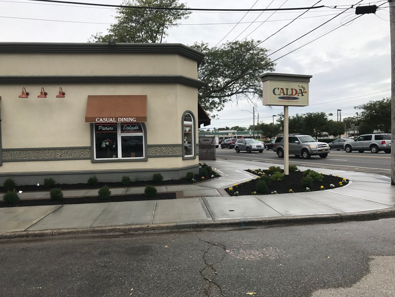 Exterior of Caldo's restaurant with a brown awning. Cars and a traffic island are in front.