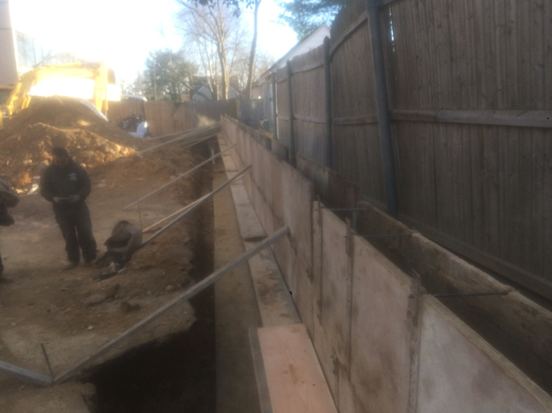 Construction site with wooden formwork, metal supports, and a trench.