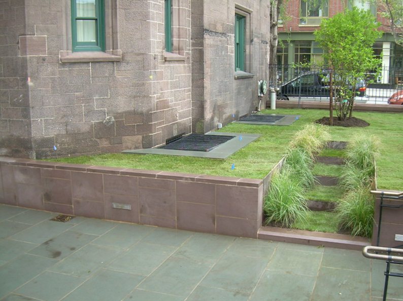 Stone building exterior with a small garden and grass steps.