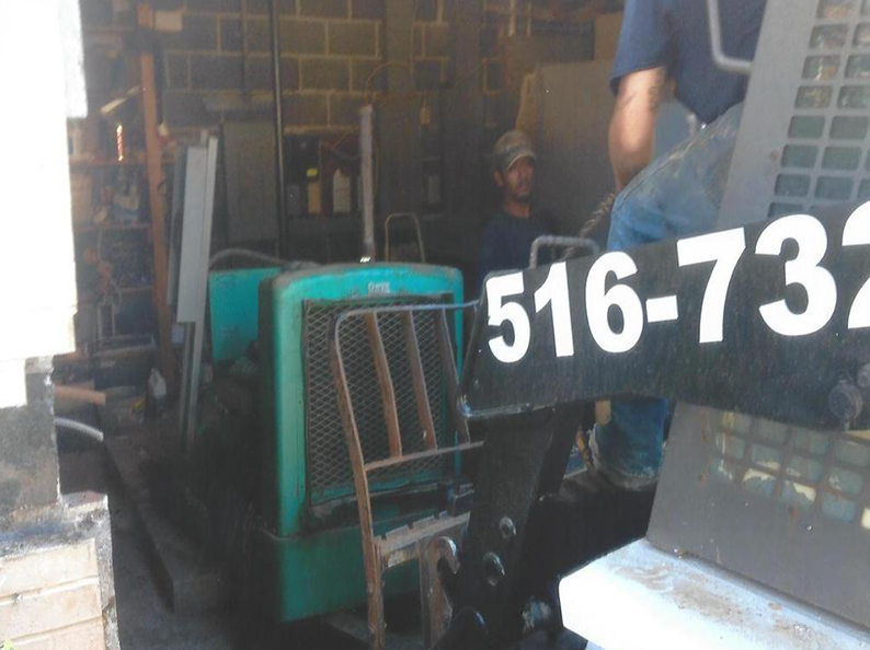 Man operates a teal machine; a second man and a sign with a phone number are also visible.