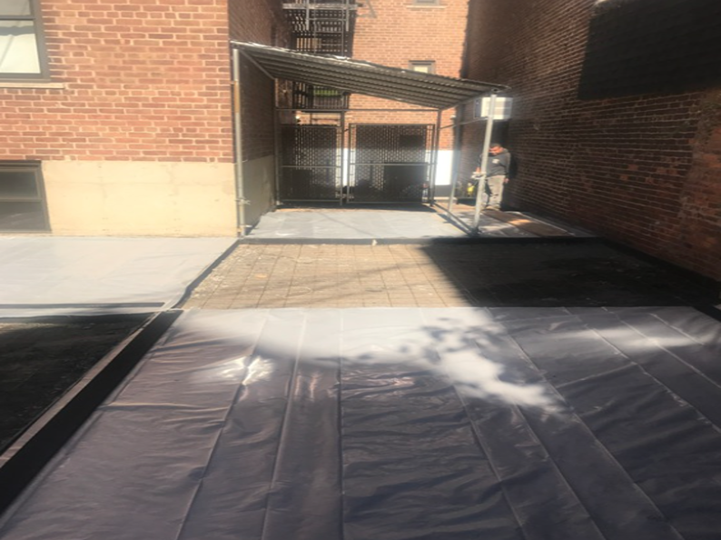 A tarp covers a partially finished outdoor area with brick walls.