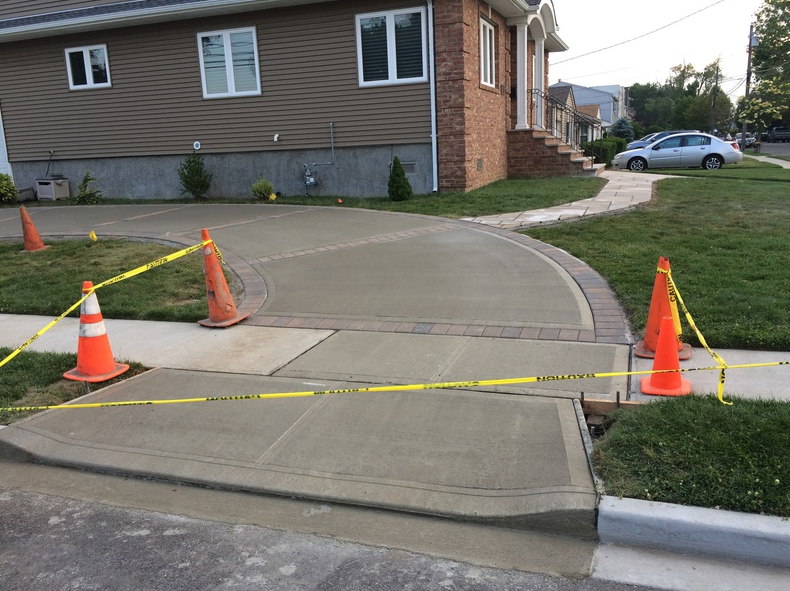 Freshly poured concrete driveway sectioned off with tape and cones.