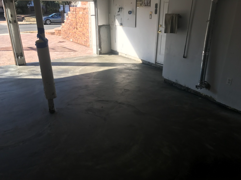 Empty garage with gray concrete floor, open door to street view.