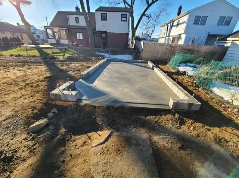 Concrete slab foundation with cinder block perimeter in a backyard.