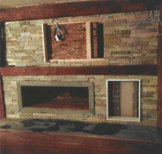Stone fireplace with rectangular opening. A wooden frame holds wiring; another holds a doorway.
