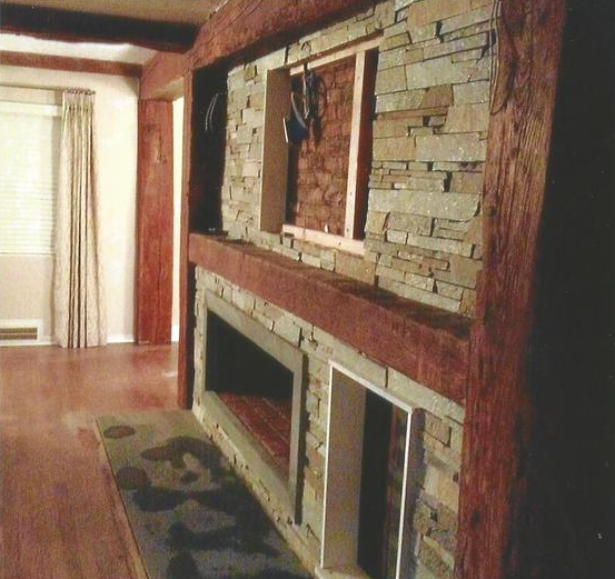 Stone fireplace with dark wood trim and recessed openings, living room setting.