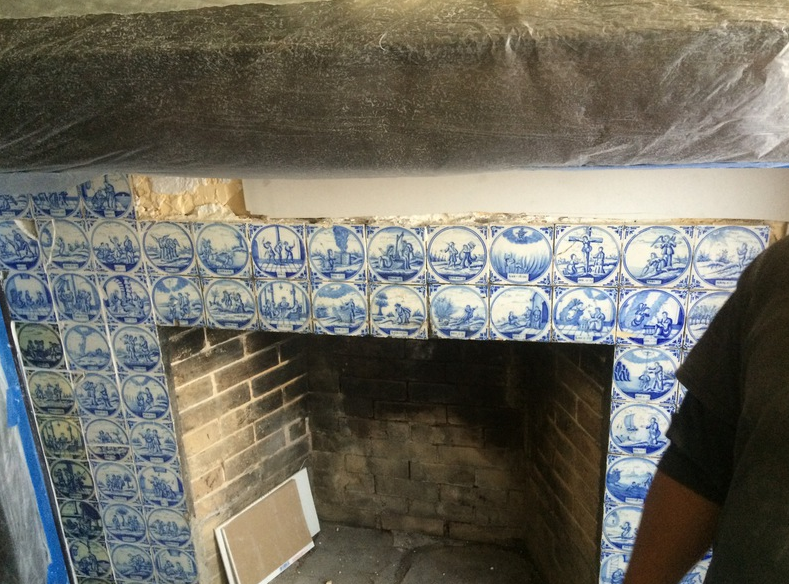 Fireplace with blue and white tiles being installed.