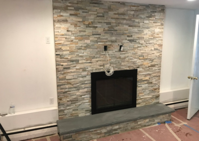 Fireplace with stone veneer, gray hearth, and white walls.