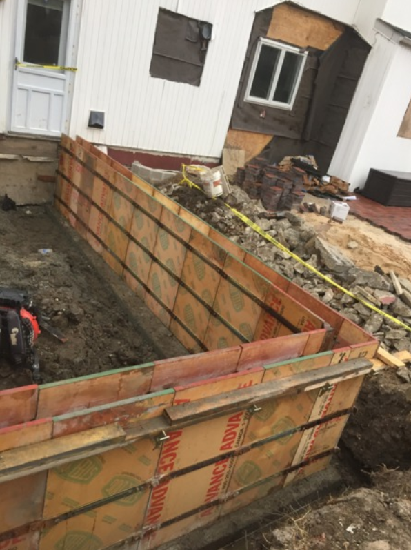 Wooden forms for a foundation wall under construction at a house.