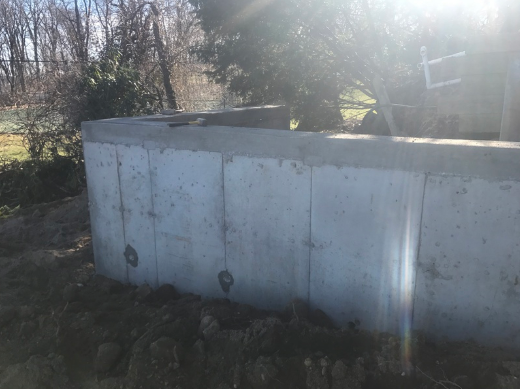 Concrete foundation wall in a sunny outdoor setting.