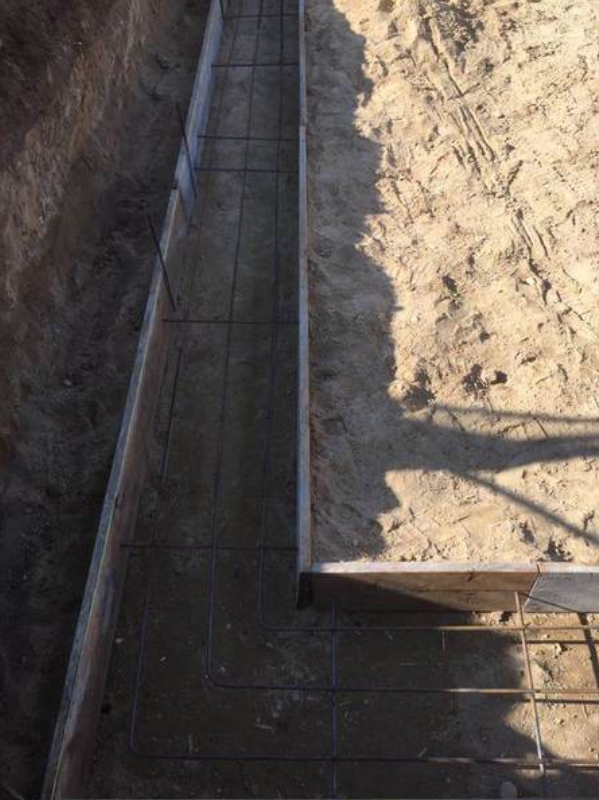 Wooden forms with rebar in a trench, ready for concrete, outdoors.