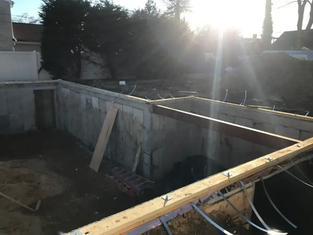 Construction site with concrete walls, wooden beams, and tools, with sunlight.