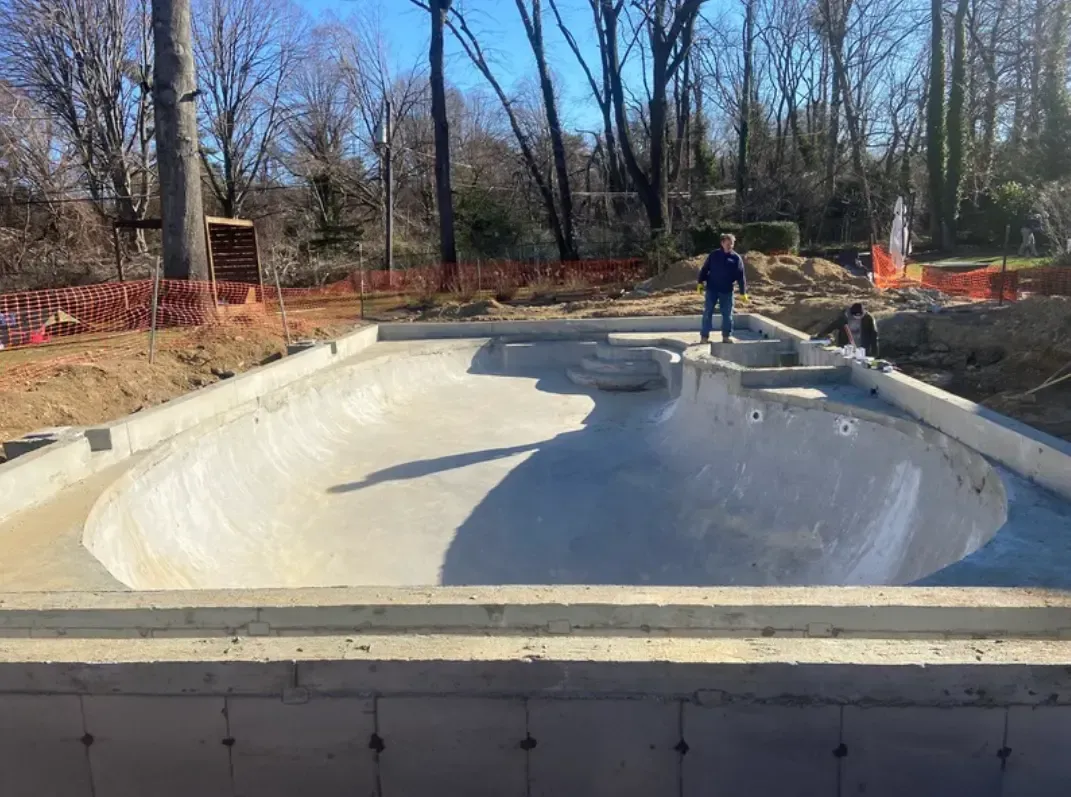 Concrete skatepark under construction with a person standing inside.