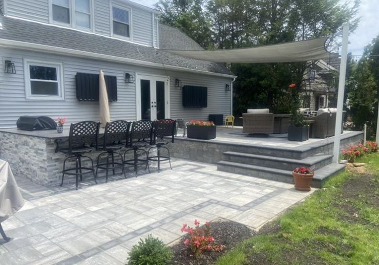 Backyard patio with bar, grill, seating, and a sun shade.