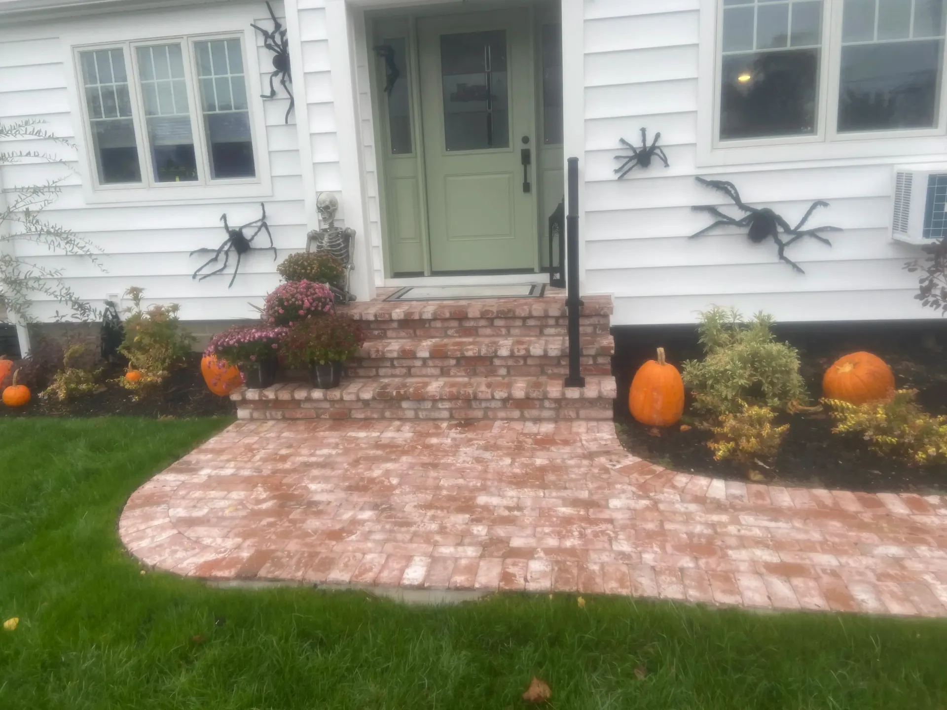 A house decorated for Halloween with pumpkins, spiders, and brick steps leading to the door.