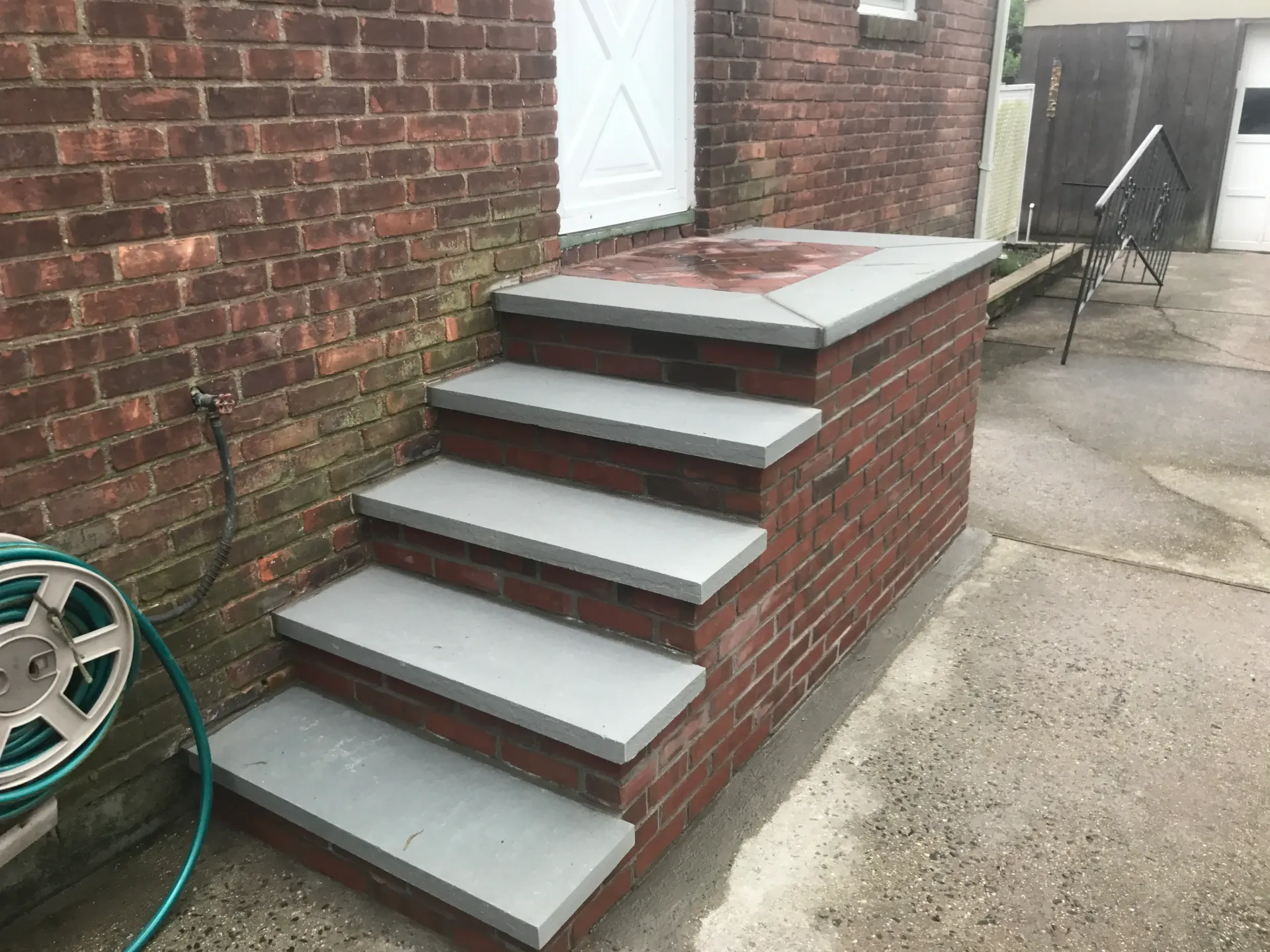 A set of stairs leading up to a brick building next to a hose.