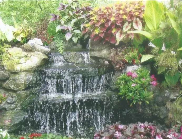 A waterfall in a garden surrounded by flowers and plants - landscape design