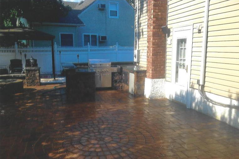Patio with brick pavers, outdoor kitchen, and a chimney.