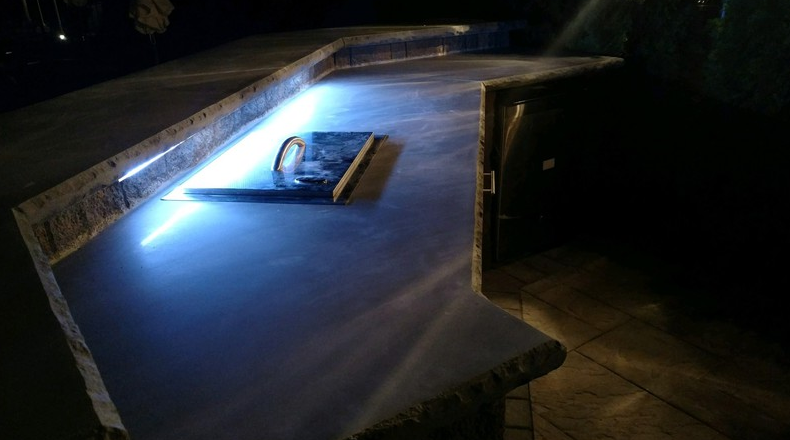 Interior of a room; bright blue light illuminating a concrete counter.