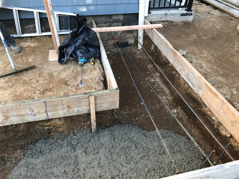 Concrete being poured into forms for a construction project outdoors, near a building.