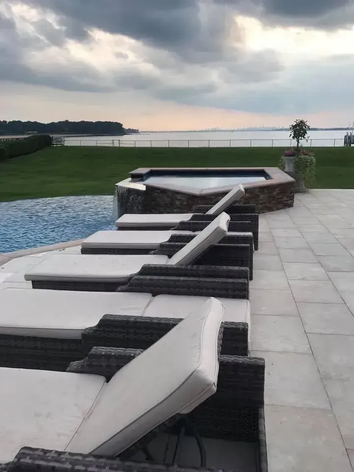 A row of lounge chairs are lined up next to a pool.